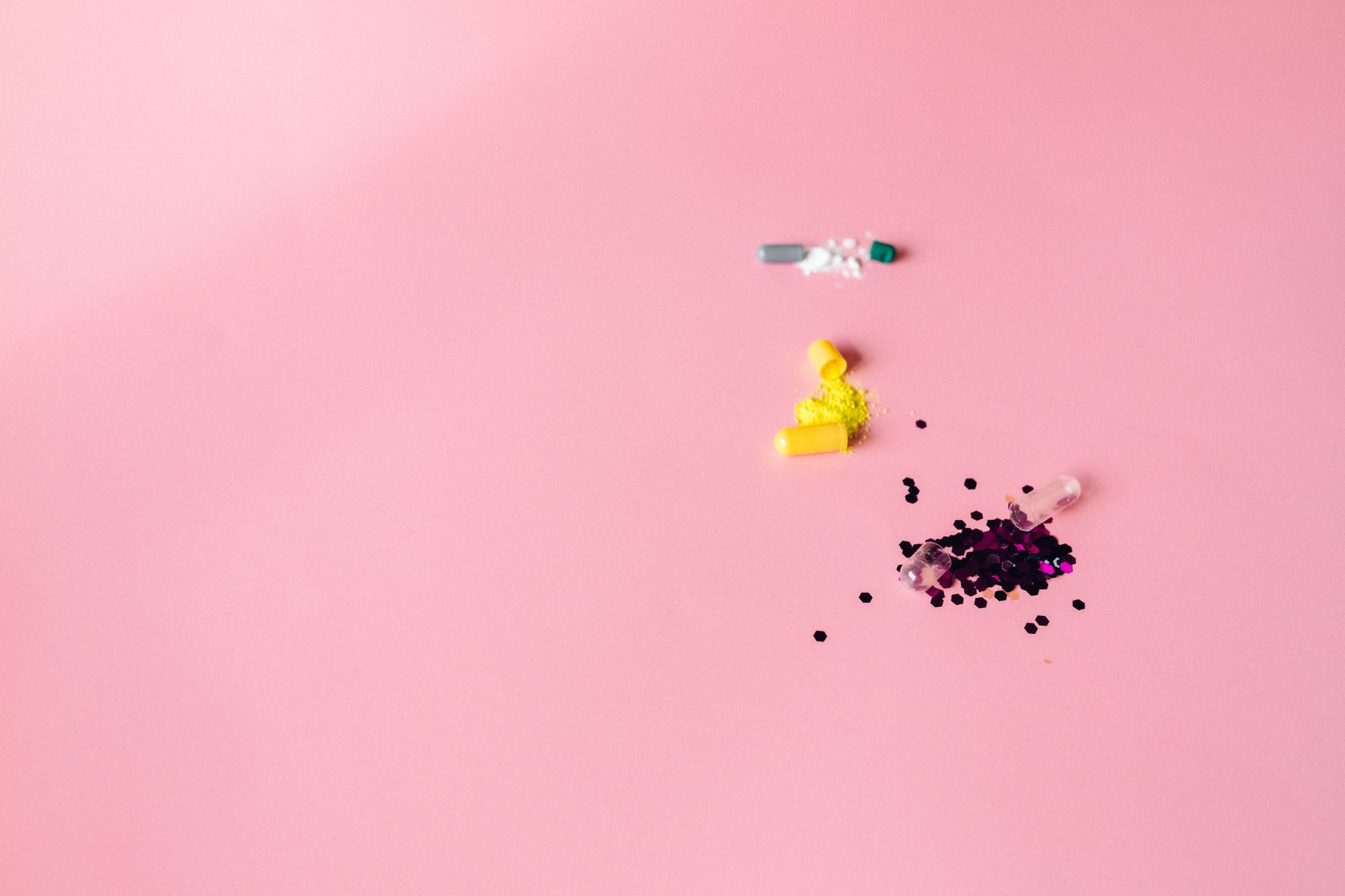 Cápsulas abiertas sobre fondo rosa para una guía sobre vitaminas en menopausia