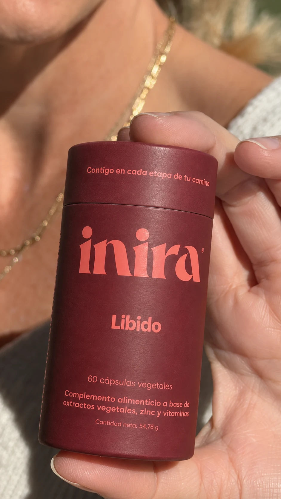 Envase de Inira Libido sostenido en la mano bajo la luz del sol